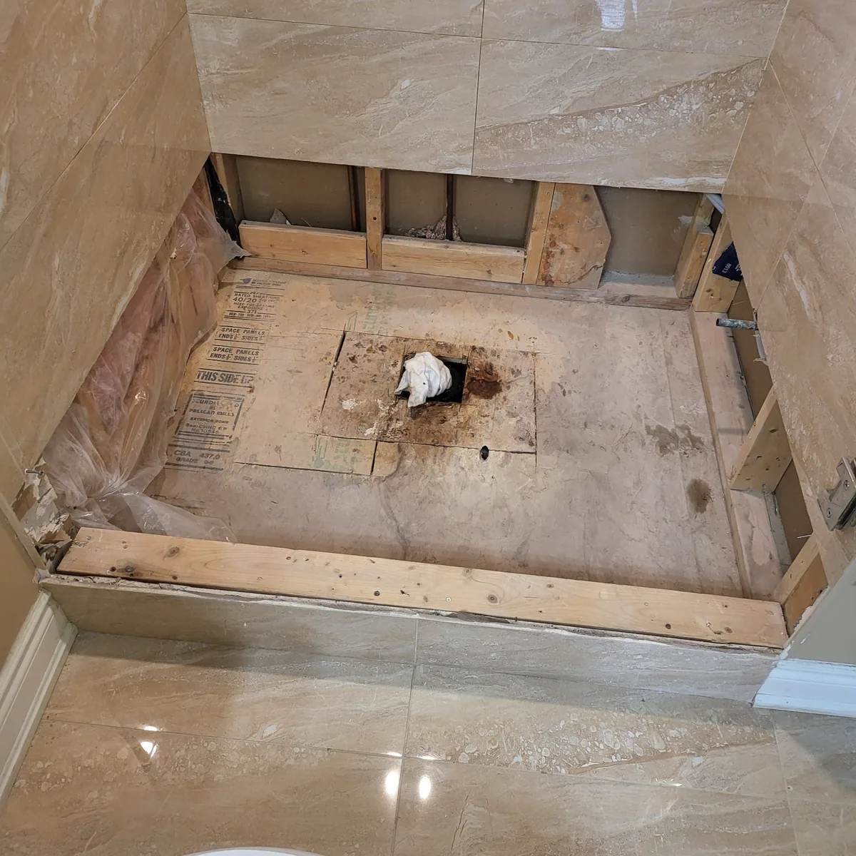 Bathroom floor opened up to the joists to reroute the drain, with the tiled walls already complete