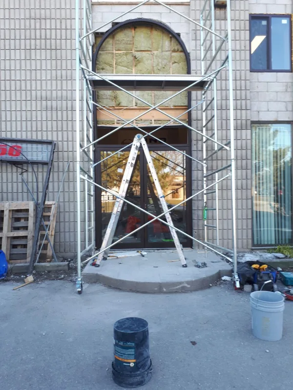 Arched entrance framed into a commercial building facade, scaffolding still in place