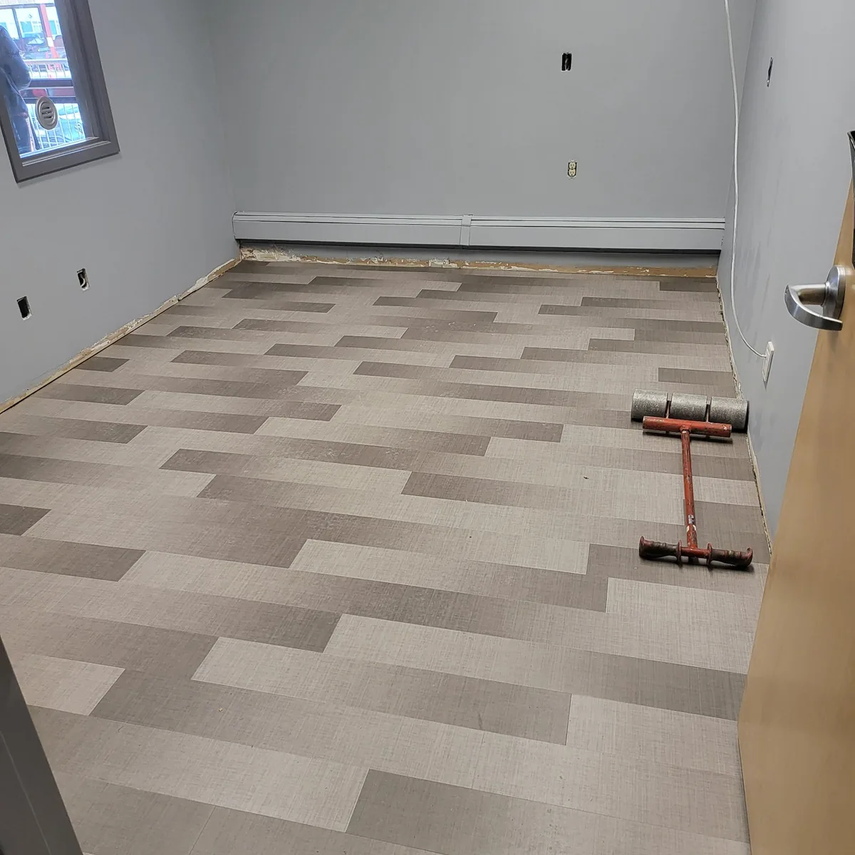 Finished commercial room with new patterned plank flooring laid wall to wall and freshly painted walls