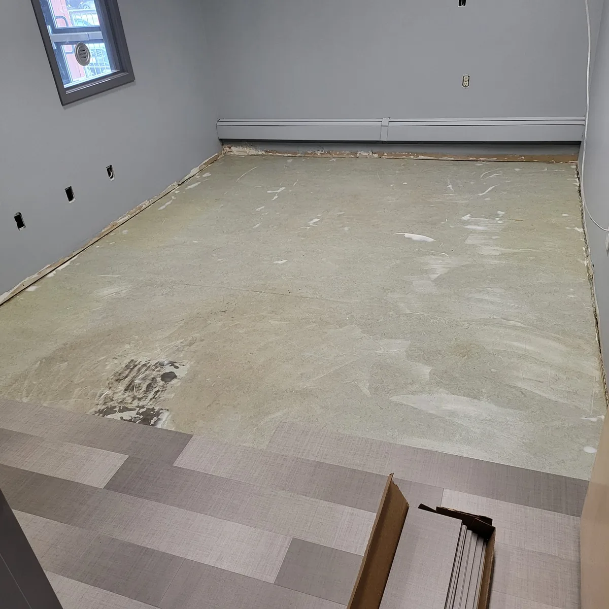 Commercial room with the subfloor levelled and prepared, new plank flooring starting along one edge