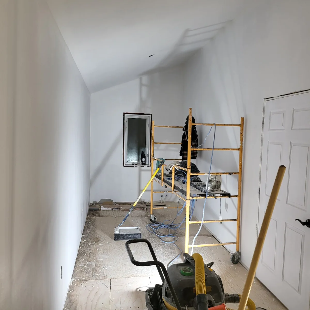 Interior room with scaffolding set up for ceiling and drywall work, walls boarded and taped