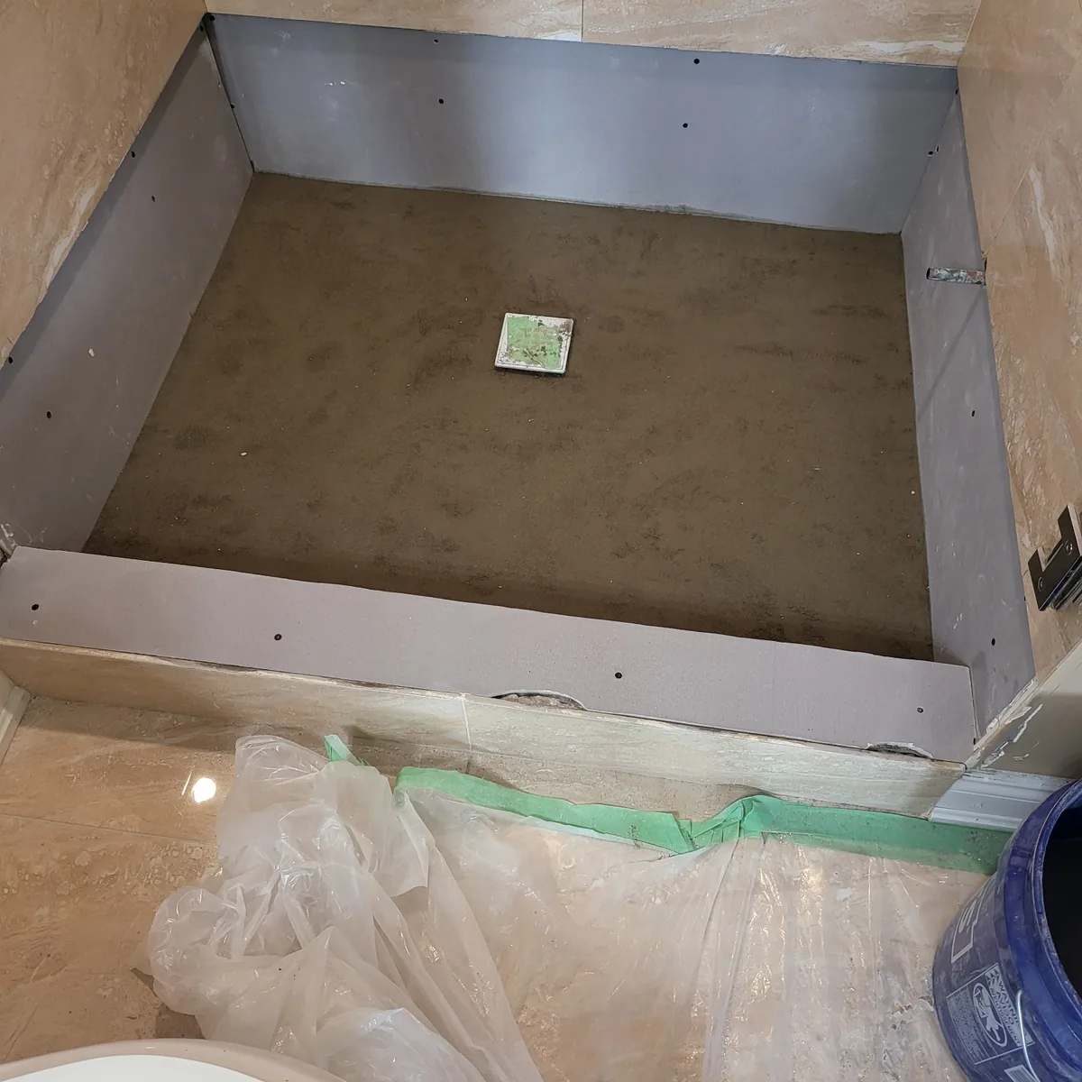 Shower pan waterproofed and sloped to the drain, ready for tile, with the walls already finished